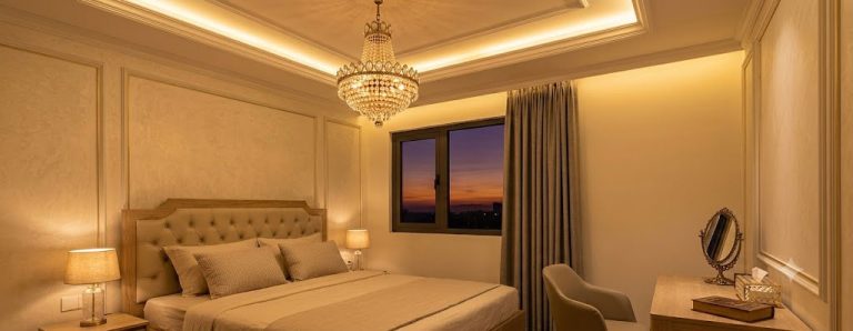 Phòng ngủ buổi tối với đèn chùm giảm độ sáng, ánh vàng dịu kết hợp đèn hắt trần